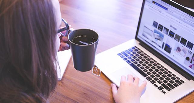 紅茶を飲みながらパソコン操作する女性