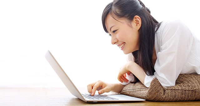 ノートパソコンを操作する笑顔の女性